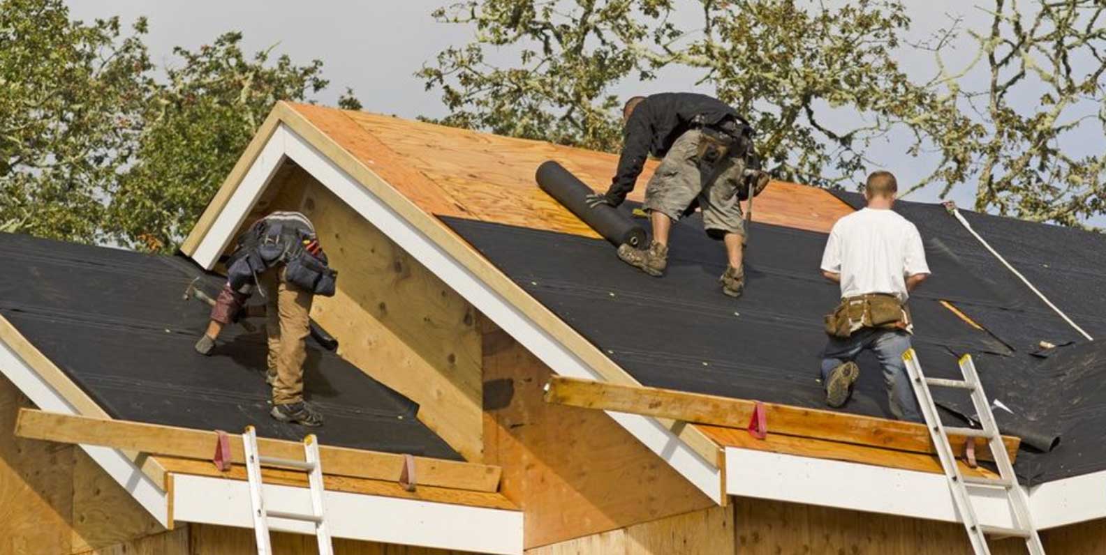 A roofing company installing synthetic felt over roof decking.